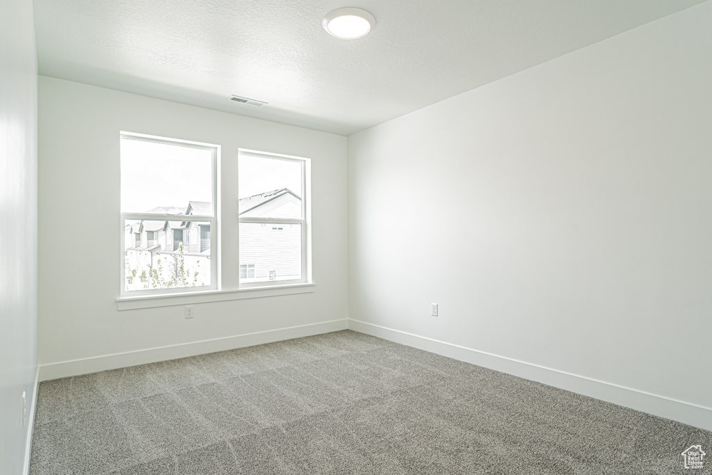 Carpeted spare room featuring baseboards