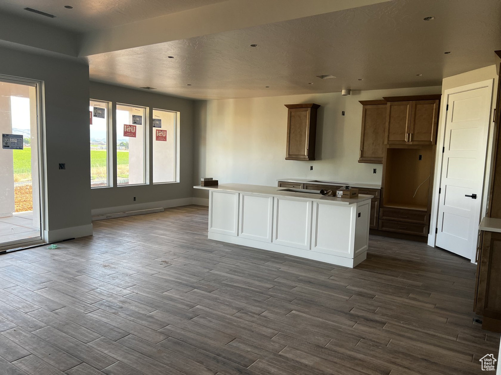 Kitchen with dark wood-style flooring, baseboards, and a center island