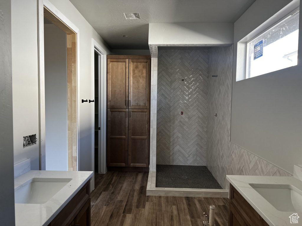 Full bath featuring vanity, tiled shower, and wood finished floors
