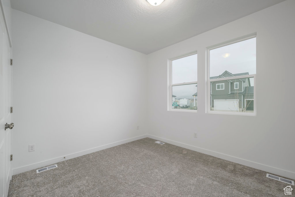 Empty room with visible vents, baseboards, and carpet floors