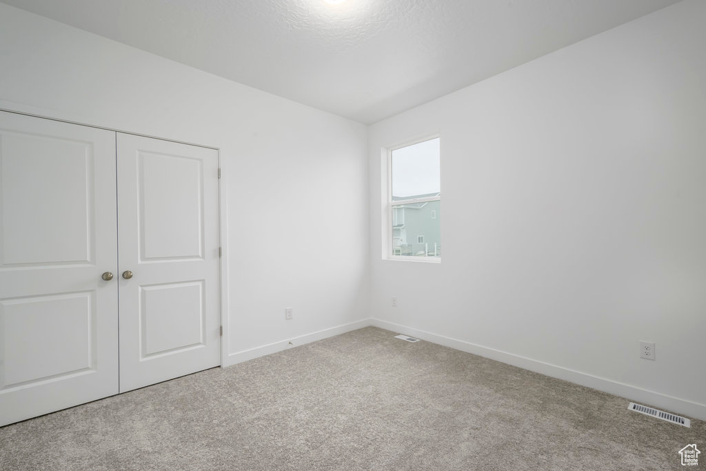 Unfurnished bedroom with visible vents, baseboards, a closet, and carpet flooring