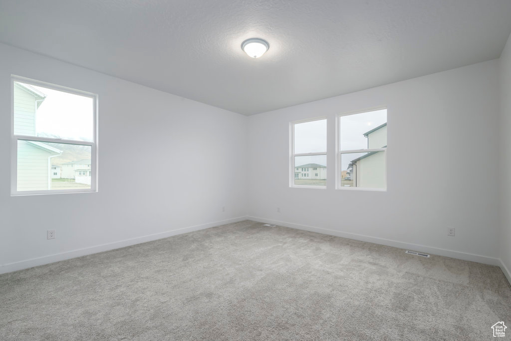 Unfurnished room with light colored carpet, a textured ceiling, and baseboards