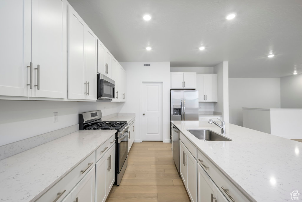 Kitchen featuring light wood-type flooring, a sink, recessed lighting, stainless steel appliances, and white cabinets