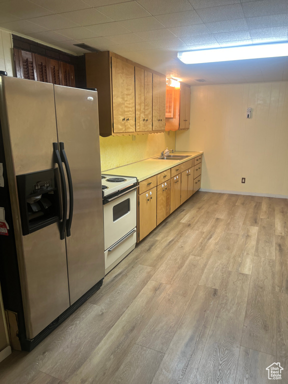 Kitchen with stainless steel refrigerator with ice dispenser, white electric range oven, light wood-style flooring, a sink, and light countertops