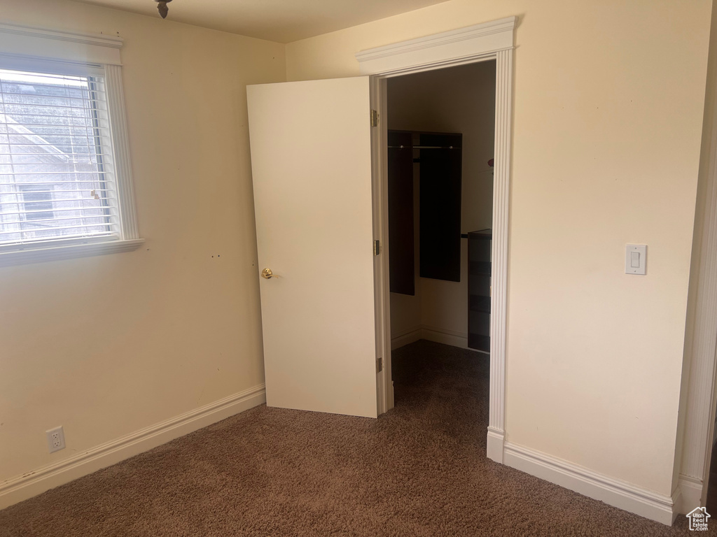 Unfurnished bedroom with a walk in closet, carpet, and a closet