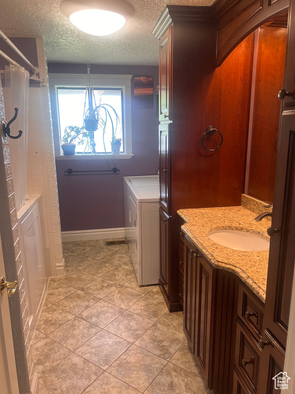 Bathroom featuring washer / dryer, a textured ceiling, curtained shower, baseboards, and vanity