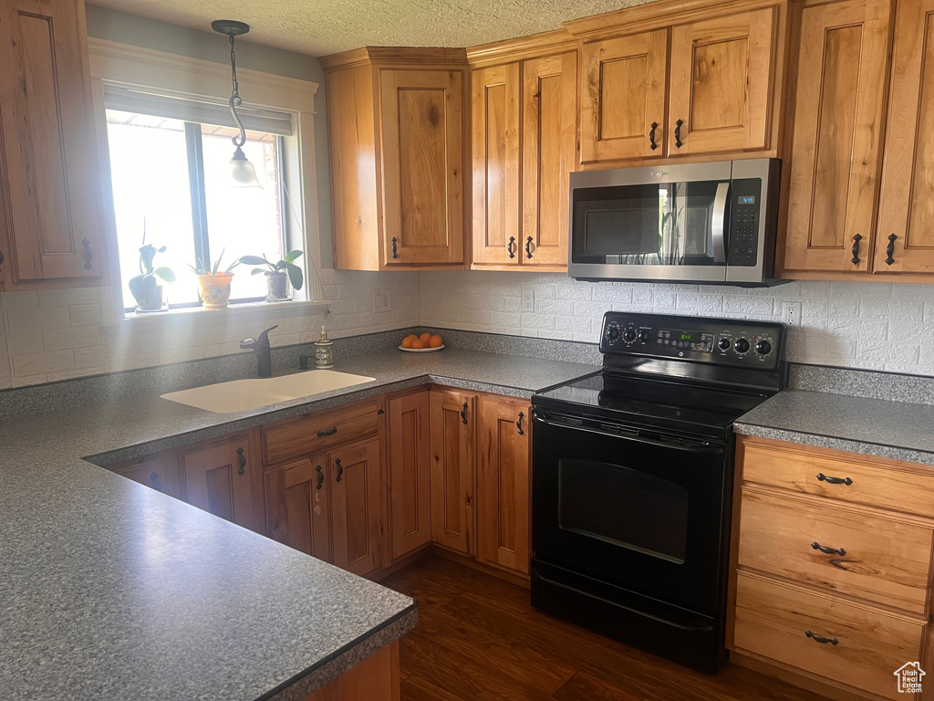 Kitchen with stainless steel microwave, electric range, a sink, dark countertops, and decorative backsplash