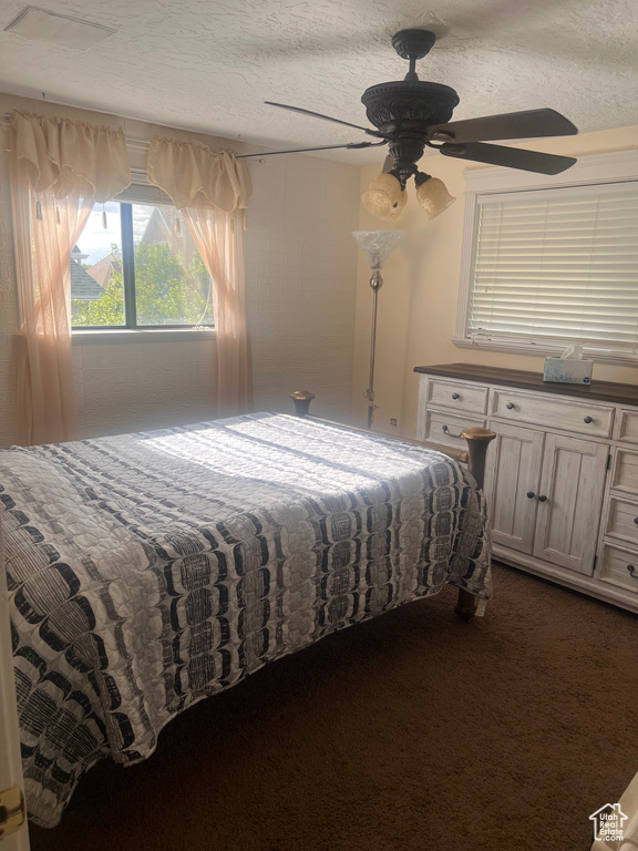 Bedroom featuring a ceiling fan and dark carpet