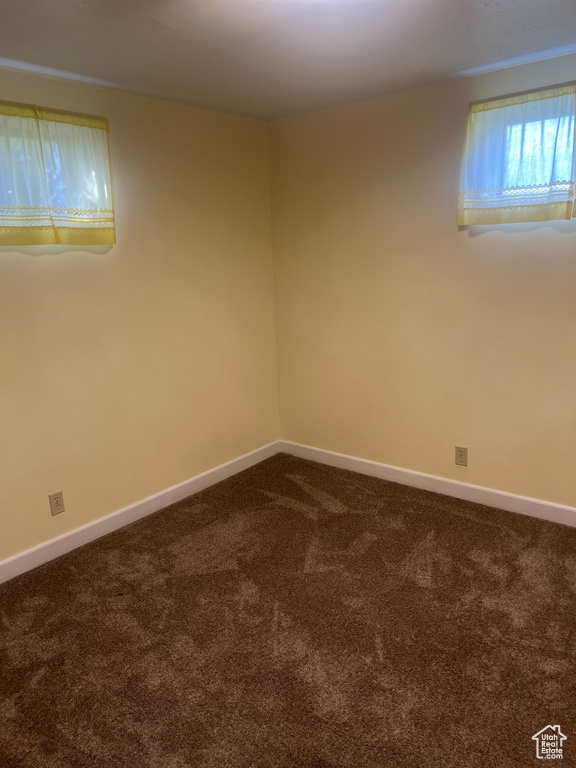 Spare room featuring dark colored carpet and baseboards