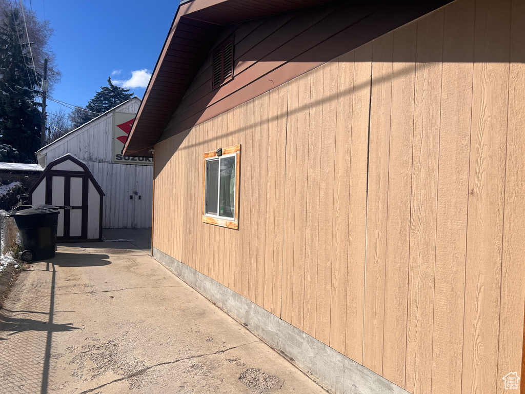 View of side of property featuring an outbuilding, a storage shed, and a patio area