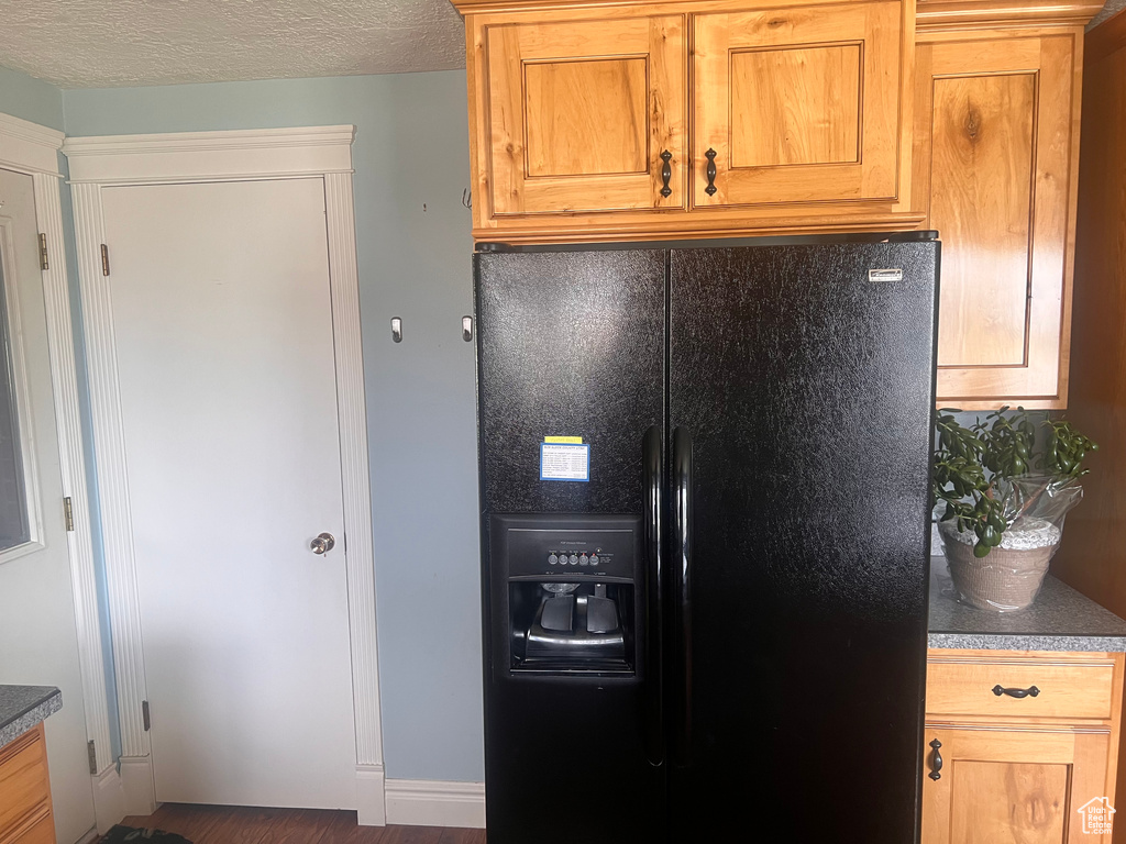 Kitchen featuring black fridge, dark countertops, and wood finished floors