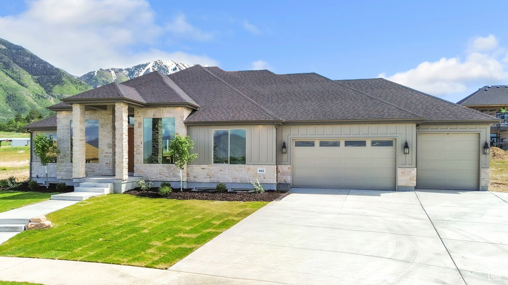 View of front of property featuring stone siding, an attached garage, and driveway