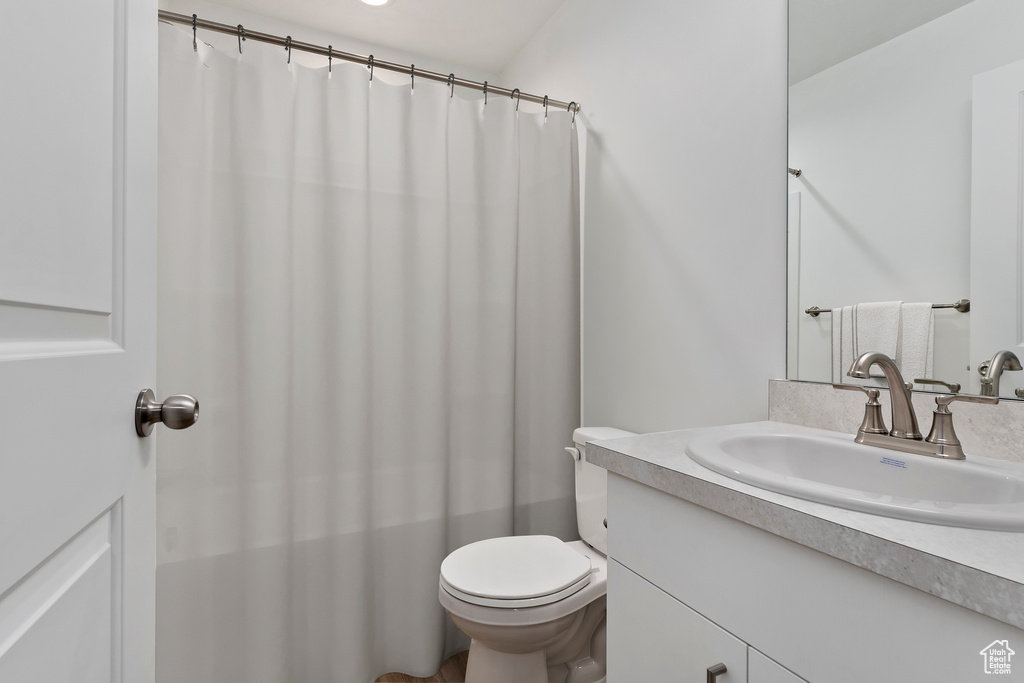 Bathroom featuring a shower with curtain, toilet, and vanity