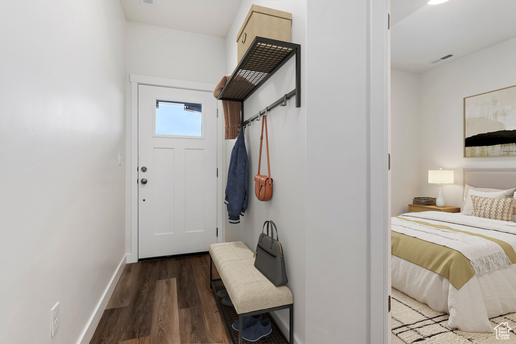 Doorway with wood finished floors, visible vents, and baseboards