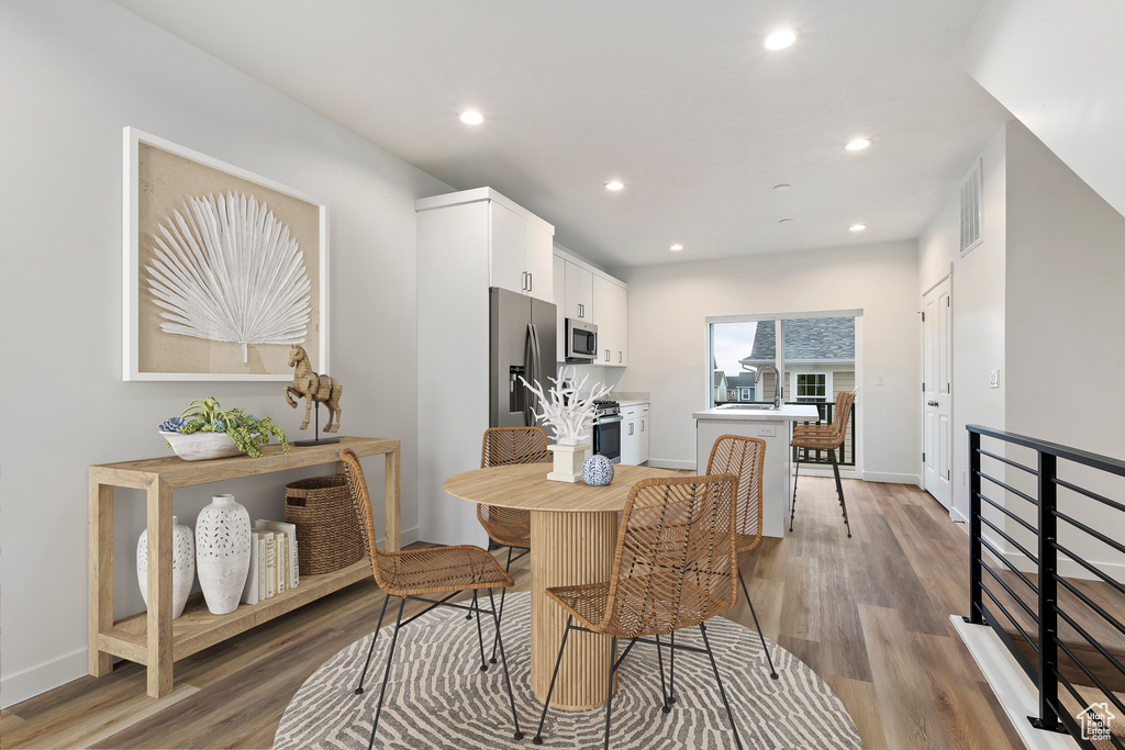 Dining room featuring light wood finished floors, visible vents, recessed lighting, and baseboards
