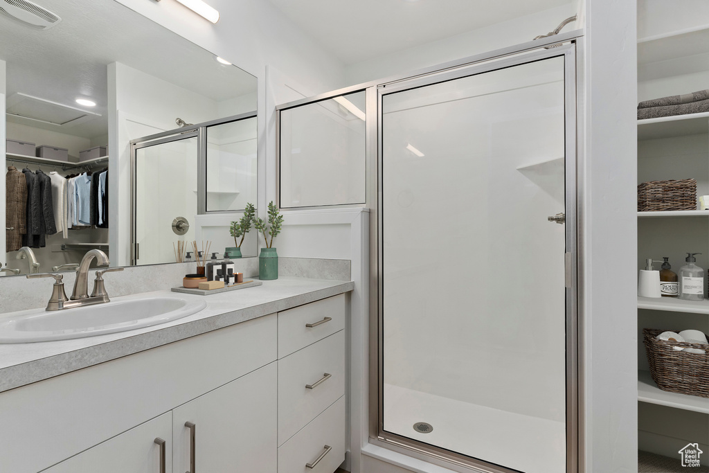 Full bath with vanity, a shower stall, and a spacious closet