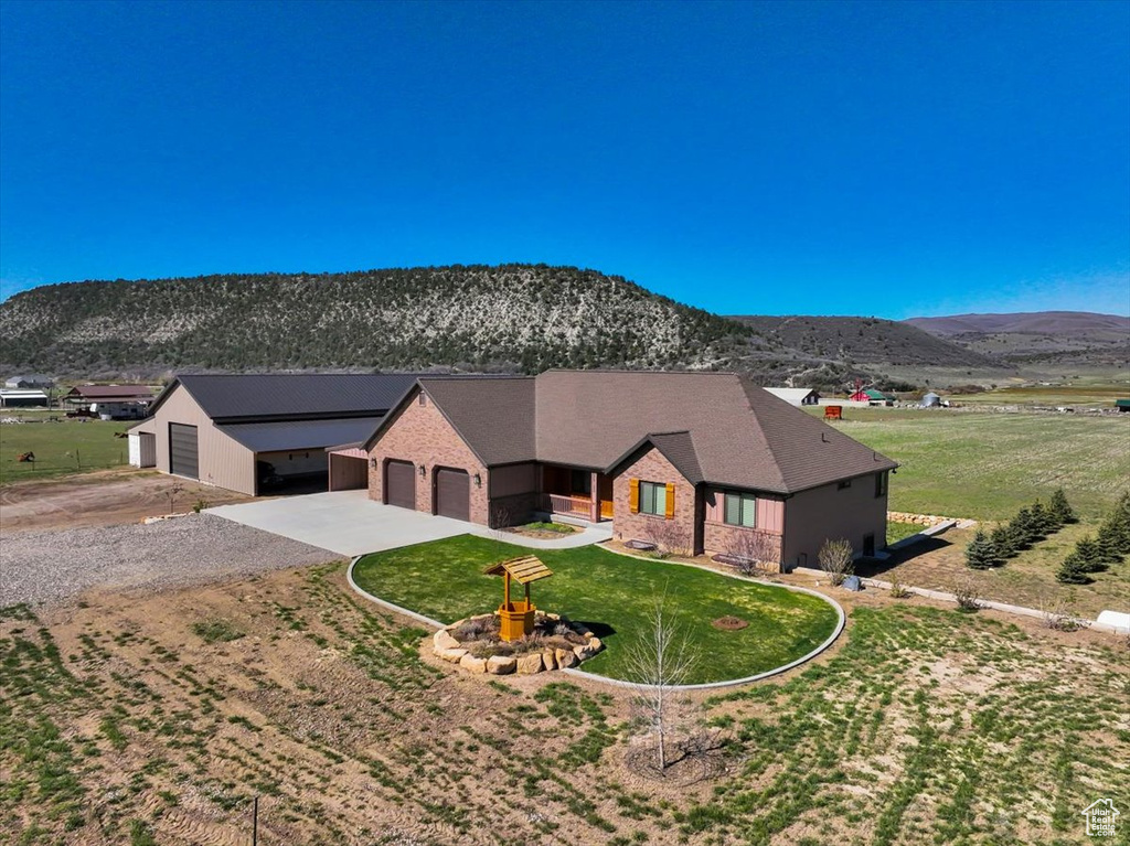 Ranch-style home with a mountain view, a garage, a front lawn, brick siding, and driveway