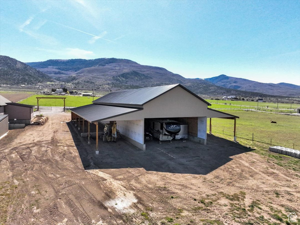 Exterior space featuring fence, an outdoor structure, a mountain view, a rural view, and dirt driveway
