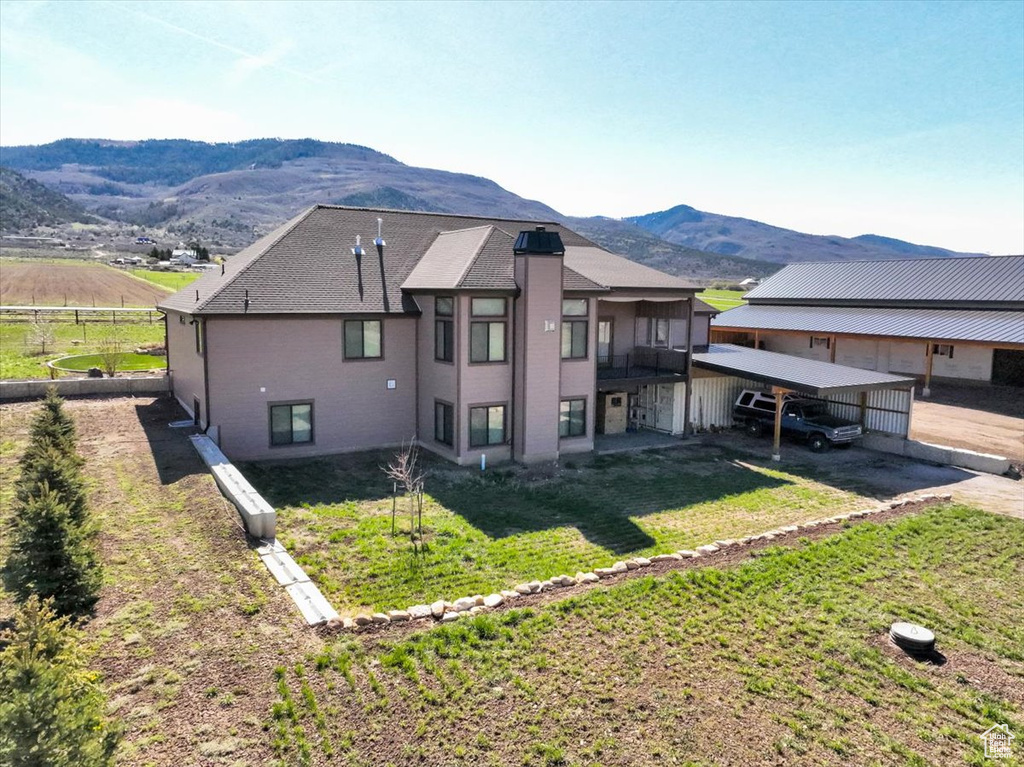 Rear view of property with a yard, fence, a mountain view, and driveway