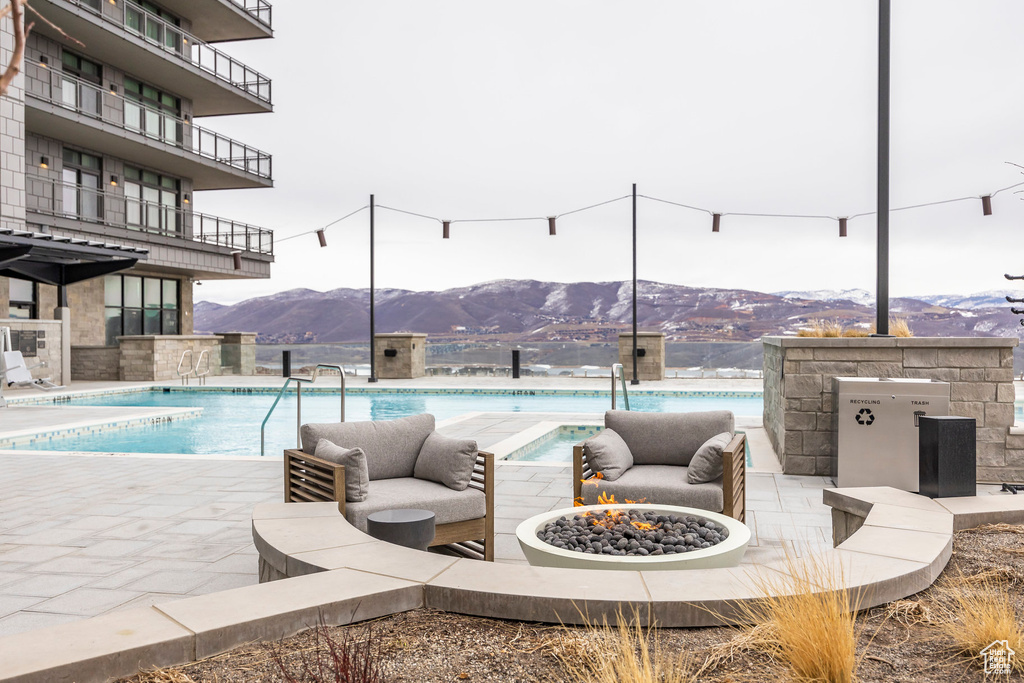 Pool featuring a mountain view, an outdoor living space with a fire pit, and a patio