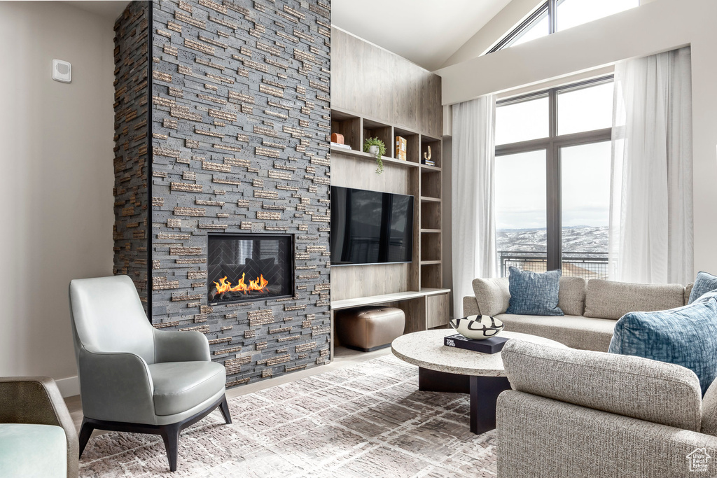 Living room featuring lofted ceiling, a healthy amount of sunlight, and a fireplace