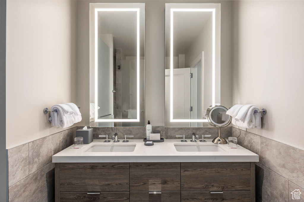 Full bathroom featuring tile walls, double vanity, wainscoting, and a sink