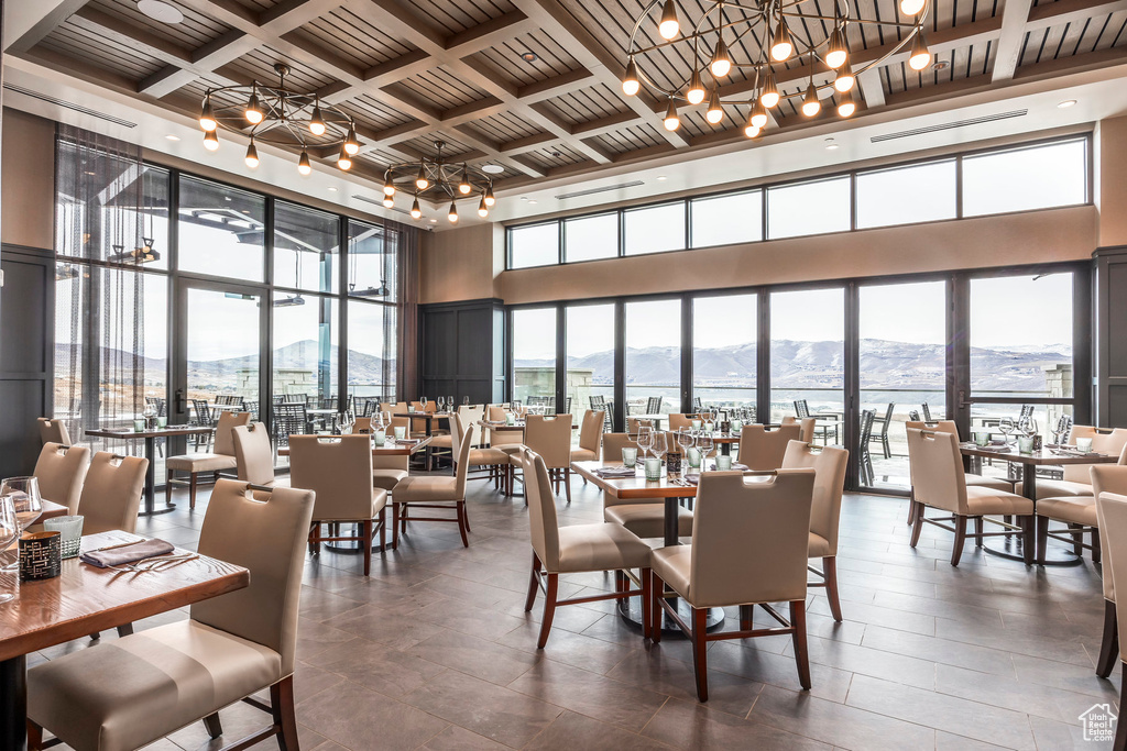 Dining area with a mountain view, a notable chandelier, a healthy amount of sunlight, and a towering ceiling