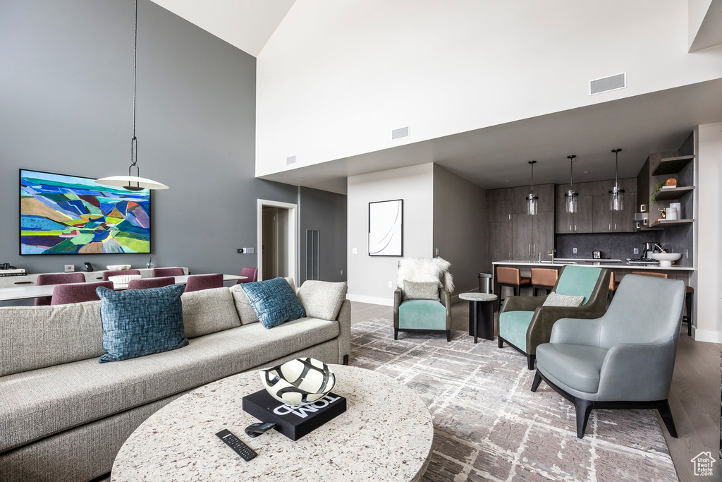 Living room featuring wood finished floors, visible vents, baseboards, and a towering ceiling