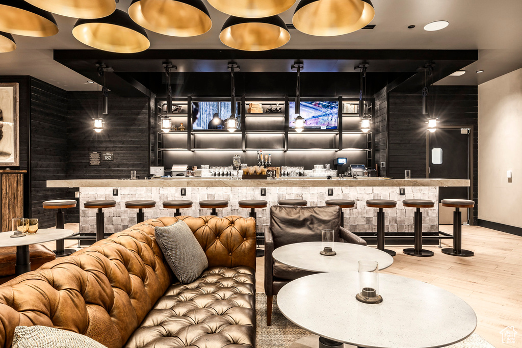 Cinema room with bar with sink, wood finished floors, and baseboards