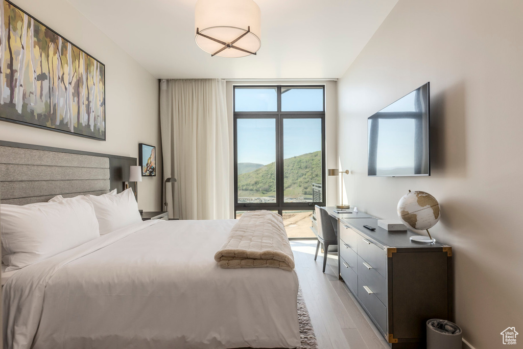 Bedroom with light wood-style flooring, access to outside, and a wall of windows