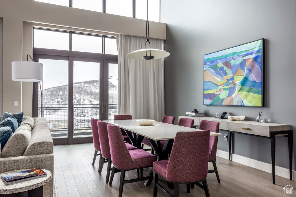 Dining space with light wood-type flooring, a mountain view, and a towering ceiling
