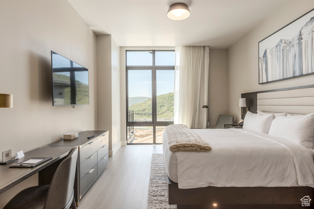 Bedroom featuring expansive windows, light wood-style flooring, a desk, and baseboards