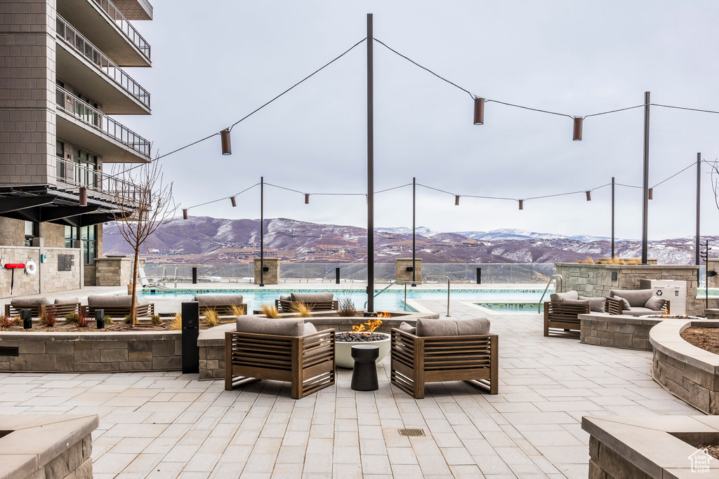 View of patio with a mountain view, a community pool, and an outdoor living space with a fire pit