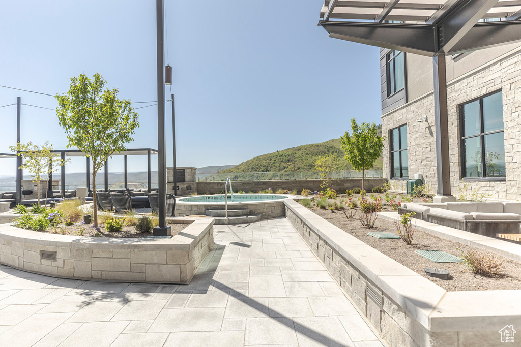 View of patio with an in-ground hot tub and a mountain view