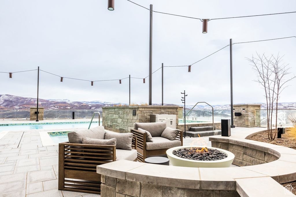 View of patio featuring an outdoor living space with a fire pit, a mountain view, and an outdoor pool