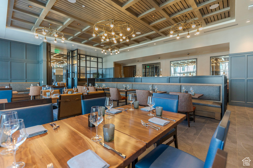 Dining room featuring coffered ceiling, a chandelier, beam ceiling, a decorative wall, and tile patterned floors