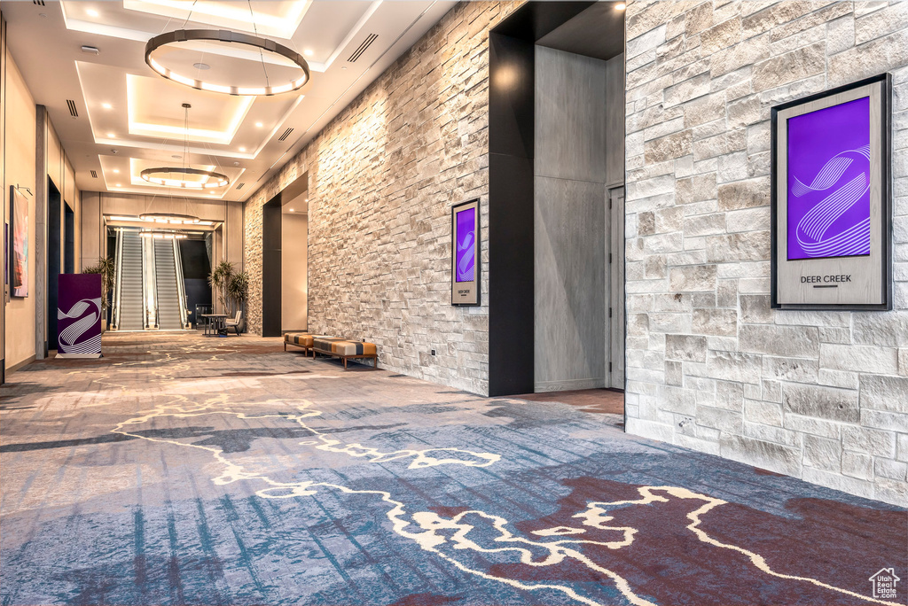 Hallway featuring a tray ceiling, a high ceiling, visible vents, and carpet flooring