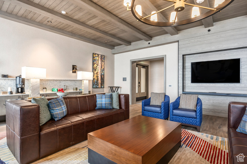 Living room featuring beamed ceiling, a notable chandelier, wood ceiling, and light wood finished floors