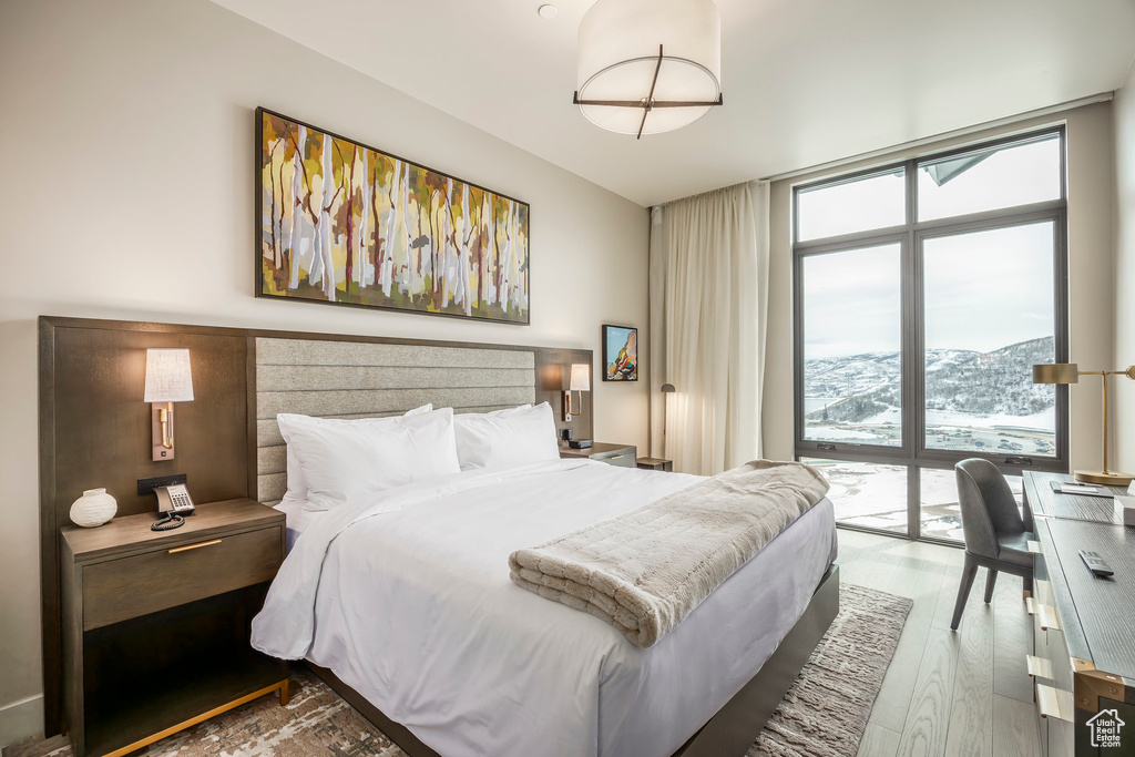 Bedroom with wood finished floors, floor to ceiling windows, and access to outside