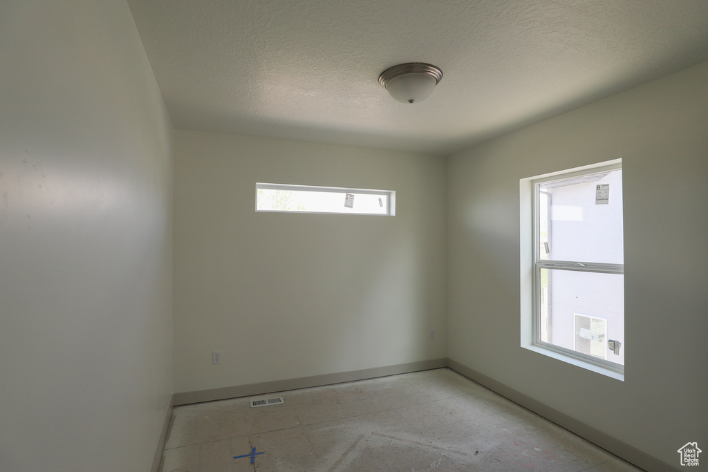 Unfurnished room with visible vents, baseboards, and a textured ceiling