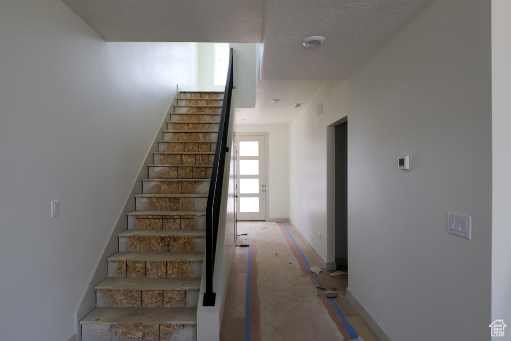 Staircase with a textured ceiling and baseboards