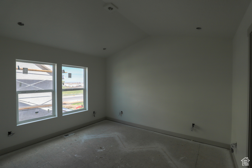 Empty room featuring visible vents, baseboards, and vaulted ceiling