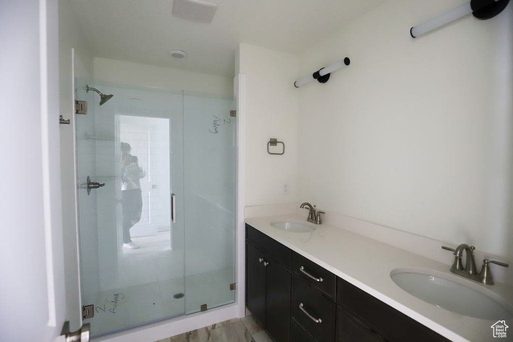 Bathroom with double vanity, a sink, and a stall shower
