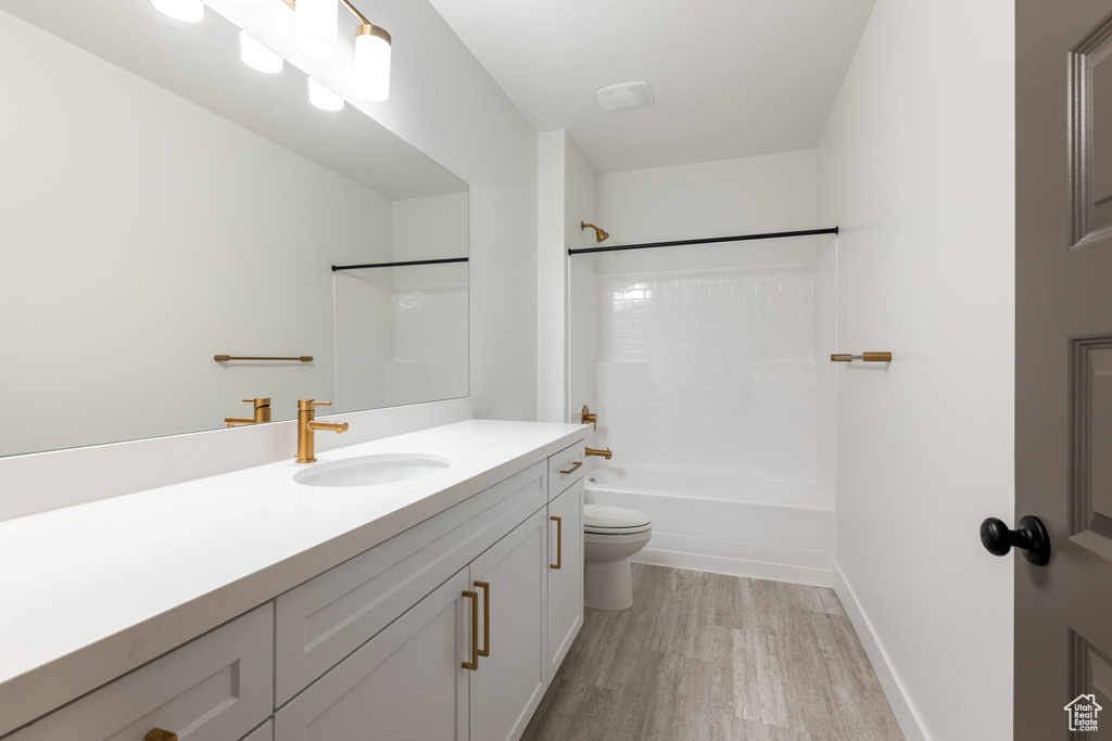 Full bath featuring washtub / shower combination, toilet, vanity, and wood finished floors