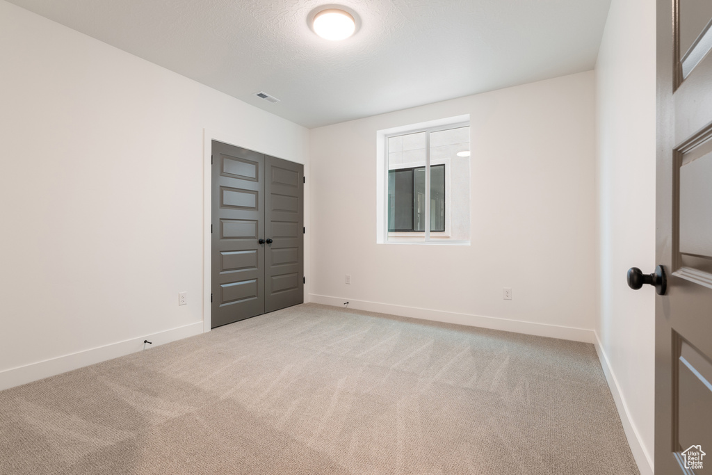 Unfurnished room featuring visible vents, baseboards, and light colored carpet