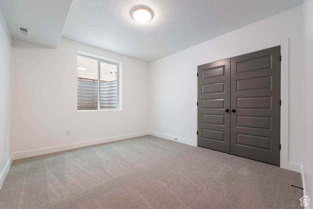 Unfurnished bedroom with visible vents, baseboards, carpet floors, a closet, and a textured ceiling