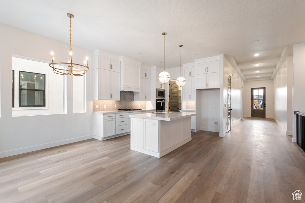 Kitchen with white cabinetry, a notable chandelier, tasteful backsplash, and appliances with stainless steel finishes