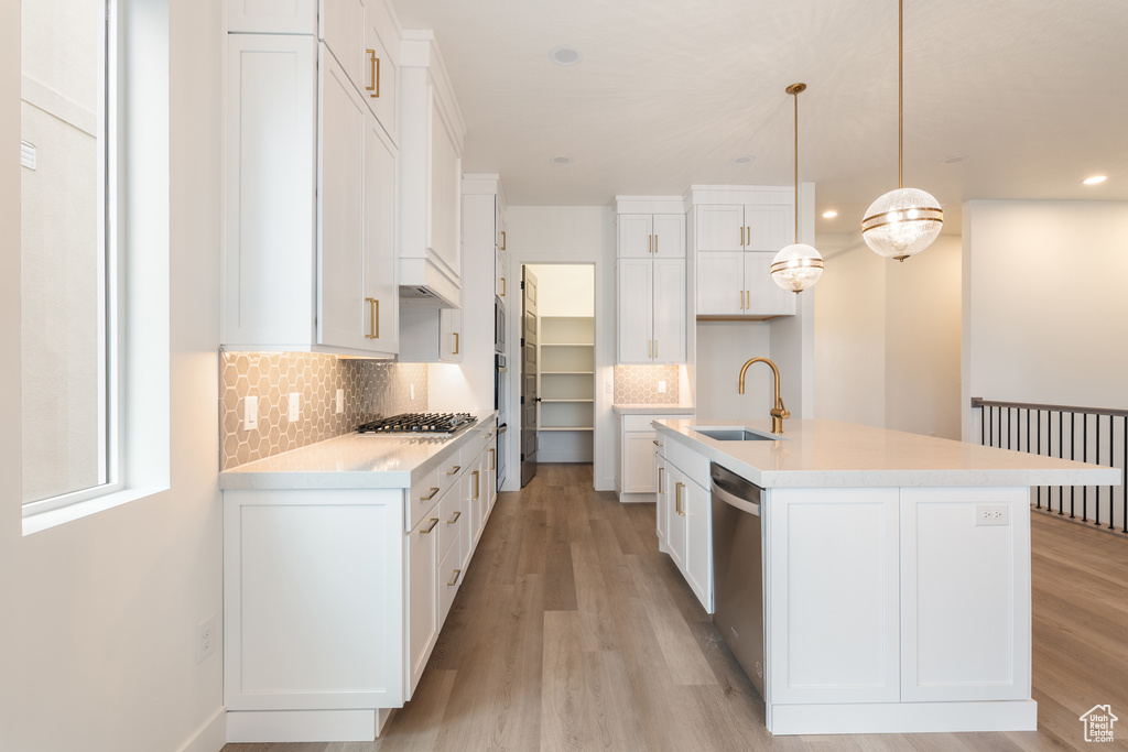Kitchen with a sink, light wood-type flooring, appliances with stainless steel finishes, and white cabinetry