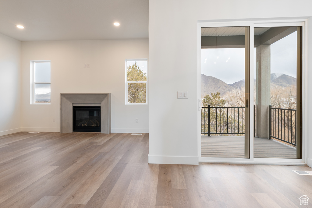 Unfurnished living room featuring wood finished floors, visible vents, a mountain view, and baseboards