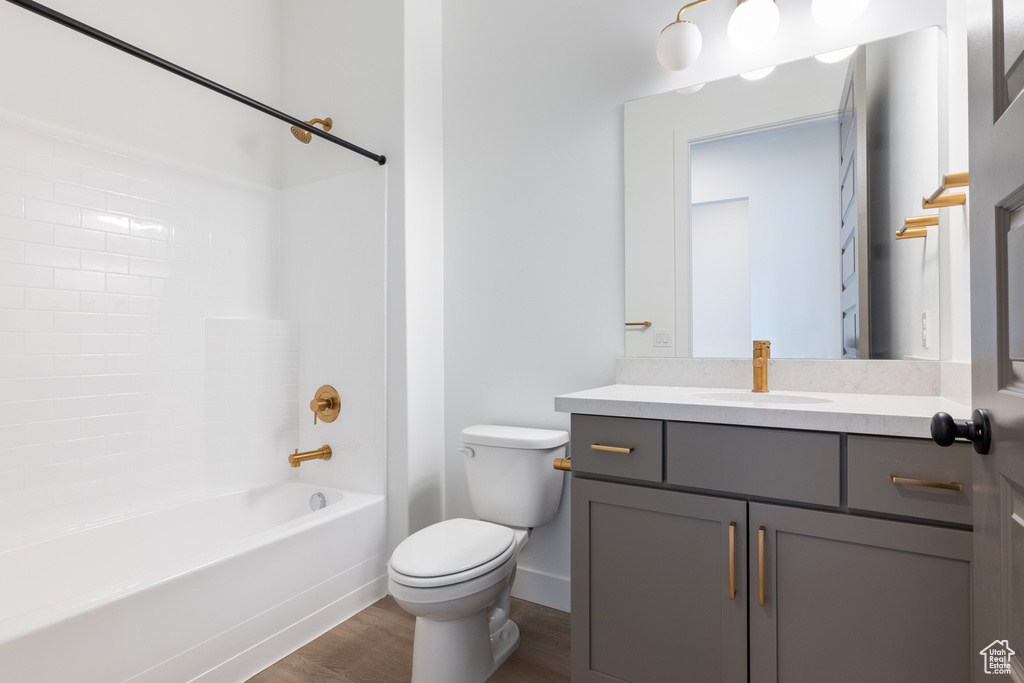 Bathroom with baseboards, toilet, bathtub / shower combination, wood finished floors, and vanity